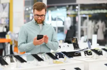 Un homme heureux choisit un téléphone portable dans un magasin d'électronique.
