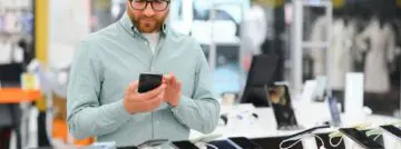Un homme heureux choisit un téléphone portable dans un magasin d'électronique.